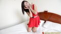 Chao kneeling on bed wearing red dress
